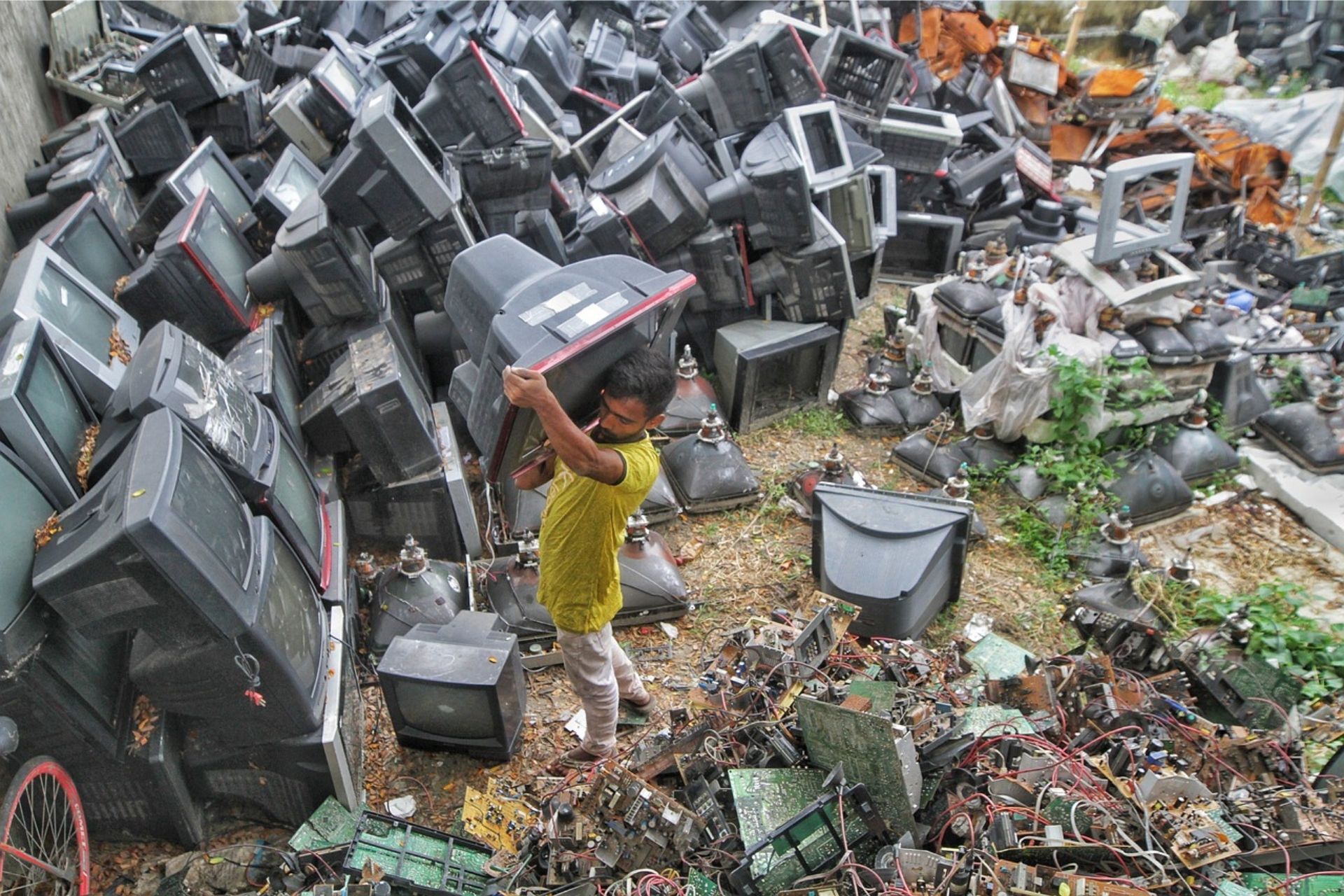 boy moving computer in pile of ewaste