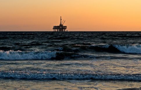 offshore oil rig seen from the beach at sunset