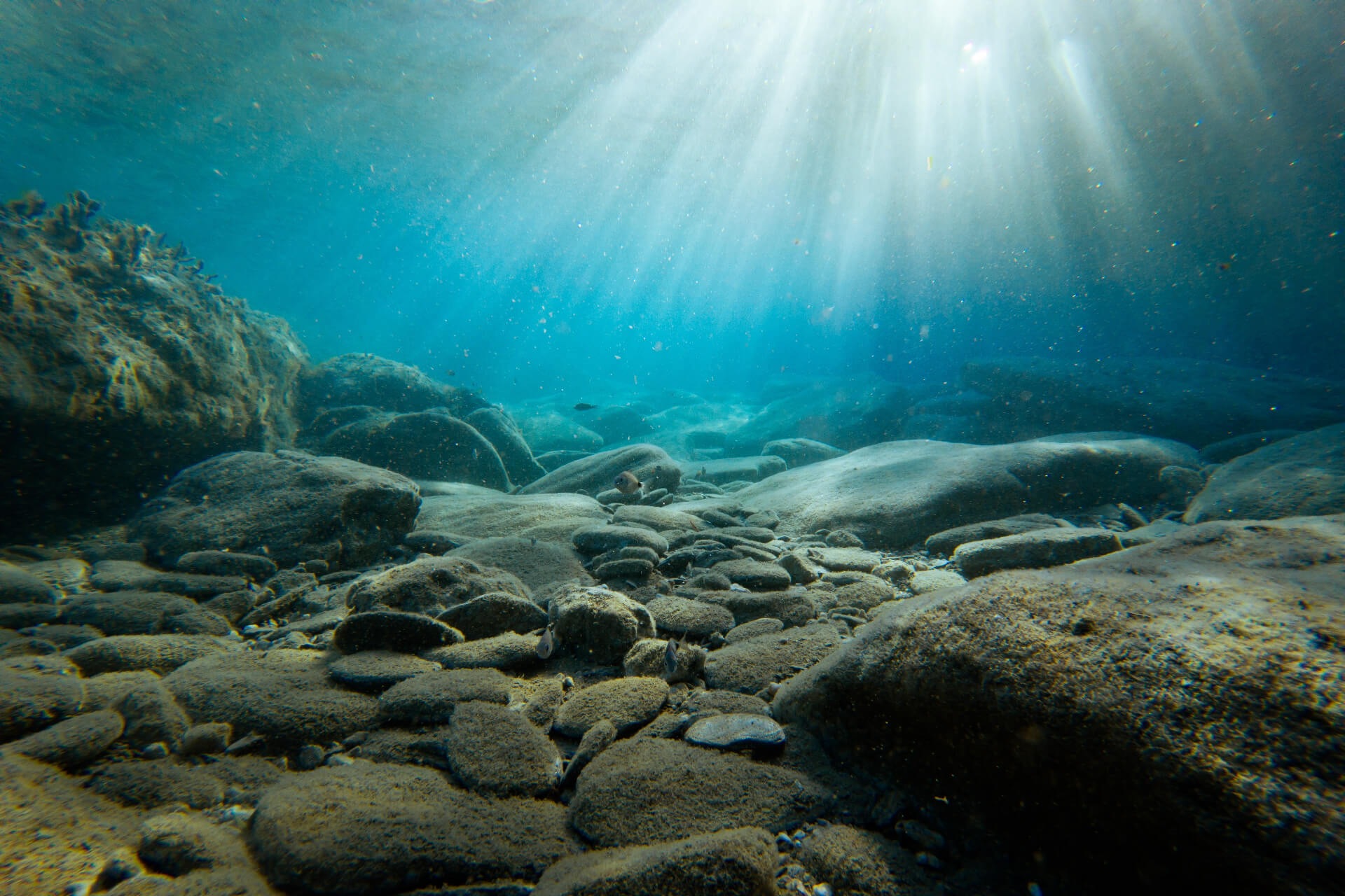 sunbeams in ocean over stones