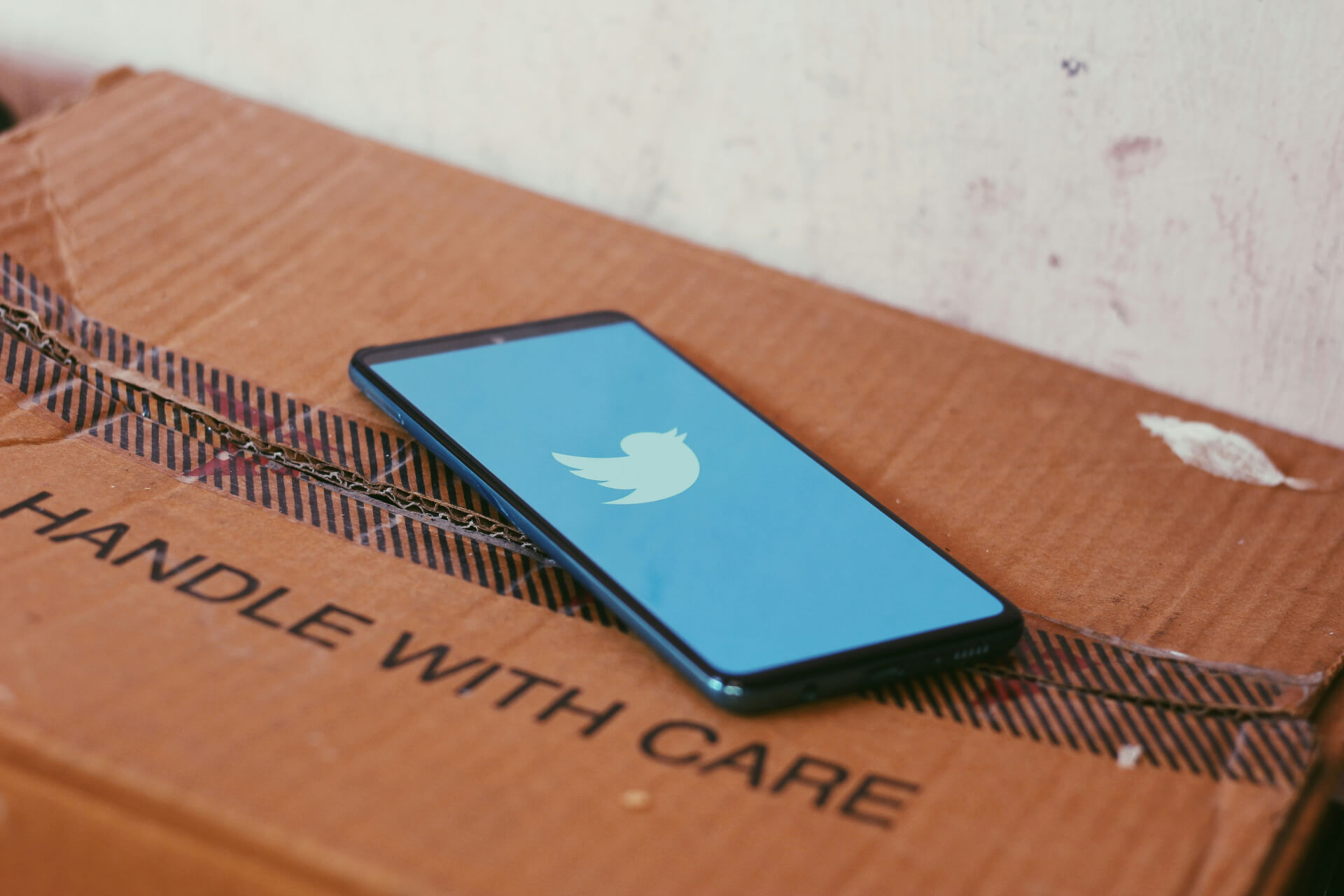 phone with Twitter open on box that says handle with care