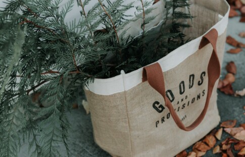 A reusable bag with greenery inside it.