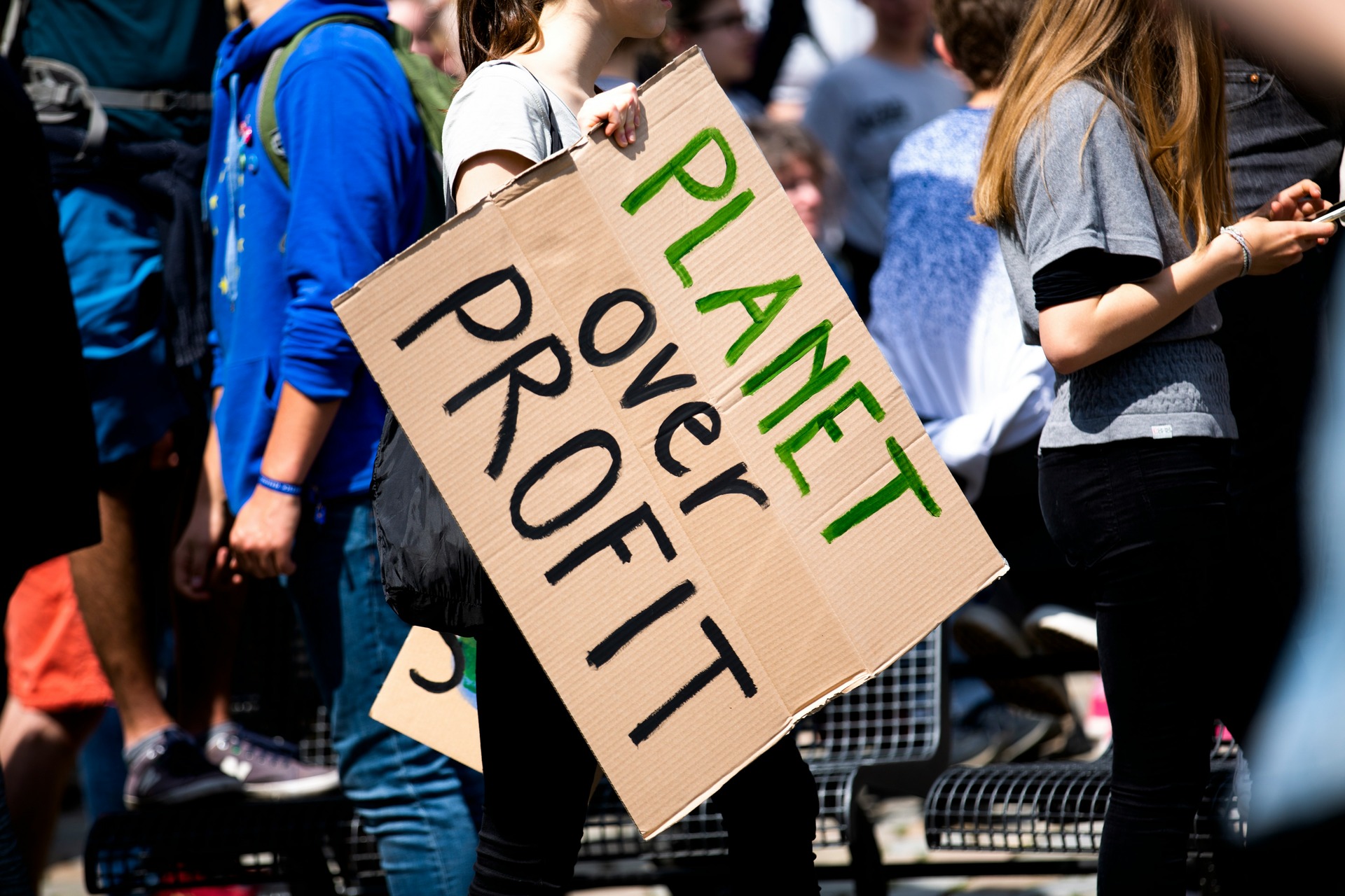 woman holding a sign that says planet over profit